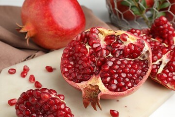 Piece of fresh pomegranate and seeds on white table, closeup