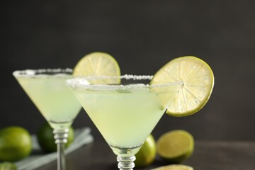 Delicious Margarita cocktail with salt and lime against blurred background, closeup