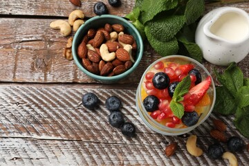 Fototapeta na wymiar Delicious fruit salad, fresh berries, mint and nuts on wooden table, flat lay. Space for text