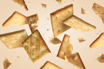 Tasty dry crackers falling on beige background