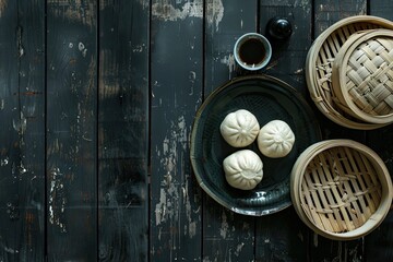 Chinese steamed buns on a plate and bamboo baskets on black wooden table with tea time