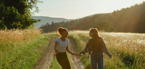 Young teenager girl best friends spending time in nature, during sunset. Girls on walk by forest,...