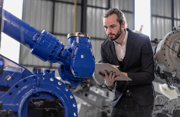 Fototapeta premium Industrial engineer manager working on robot maintenance in AI futuristic electronic technology factory. Robotic expertise checking automated machine. Modern bearded man technician in industry 4.0.