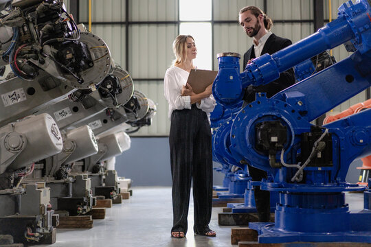 Businesswoman visit robotics engineering industry talking with engineer manager planning modern automated development technology. Group of people meeting for innovation solution efficiency in factory