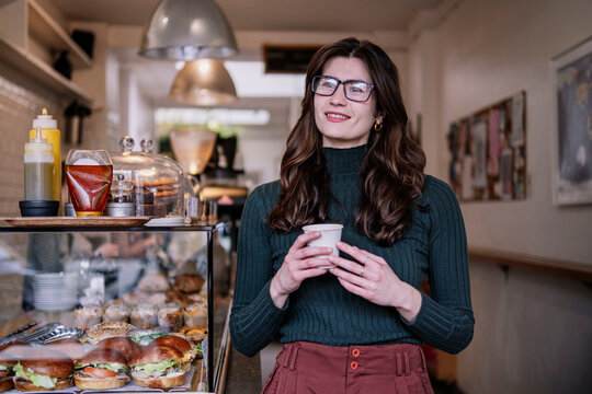 Smiling businesswoman standing near food display in cafe
