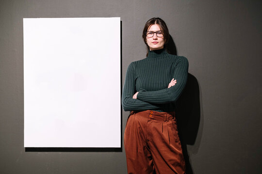 Confident businesswoman standing near white board in front of wall at office