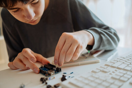 Teenage boy adjusting electrical component near keyboard at home