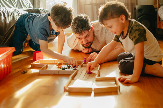 Siblings playing with toys near father at home