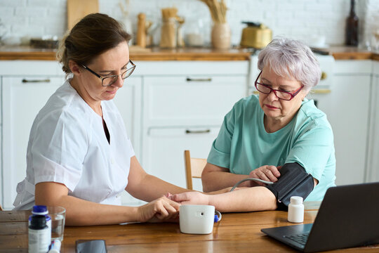 Nurse measuring blood pressure of senior woman at home