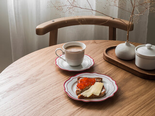 Delicious breakfast, snack - a cup of coffee and red caviar and cheese sandwiches on a round wooden table - 785061311