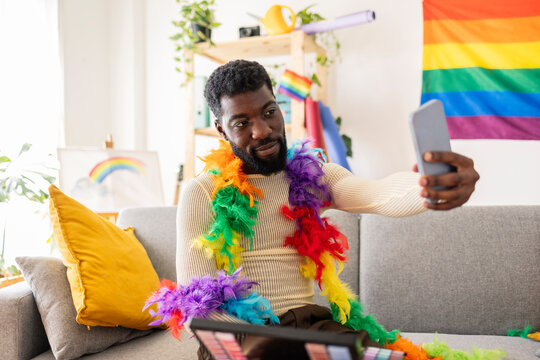 Young non-binary person taking selfie with feather boa at home