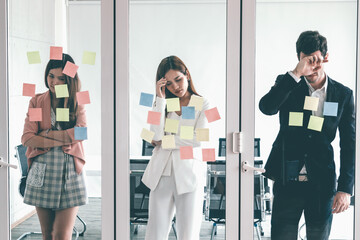 Unhappy business people feel disappointed while looking at sticky note on the windows in the...