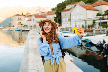 Young female tourist is exploring new city making photo on smartphone. Selfie time. Lifestyle,...