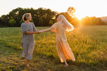 Happy friends holding hands and spinning in park