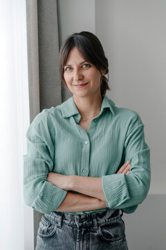Smiling woman with arms crossed inf front of wall