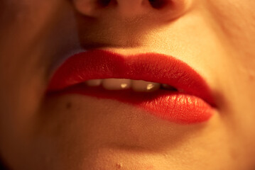 Close-up of a girl with red painted lips, passionately biting her lips.