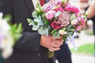 stylish-groom-holding-tender-pink-wedding-bouquet