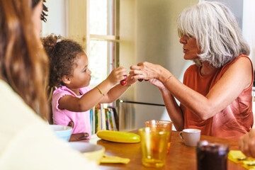 Toddler engages with their grandparent over breakfast- sharing the simple joy of fresh fruit. In a...