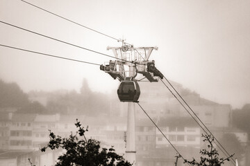 A Vilanova de Gaia cable car gondola suspended on hanging steel cables ascending under a cloudy sky...