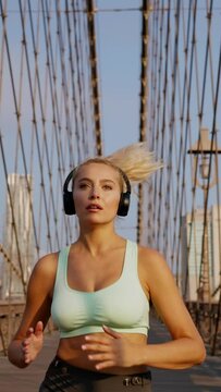 Active young blonde woman in sport clothing running while exercising outdoors