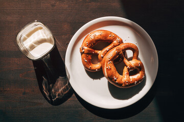 Glass of yoghurt and two pretzels on a plate on the table in the morning