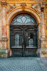 Old wooden doorway with broken glass and worn wrought iron decoration