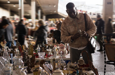 Ordinary Afro-American guy considers things sacond hands on flea market