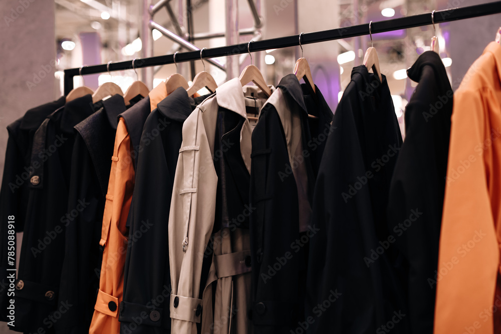 Wall mural Black orange fashion cloth hanging on a hangers in a row. Modern clothing collection