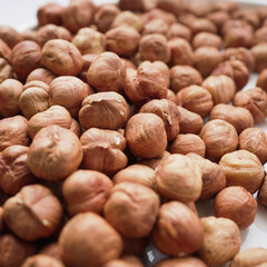 A close-up view of a pile of hazelnuts, showcasing their rich texture and warm, brown tones, perfect for culinary themes