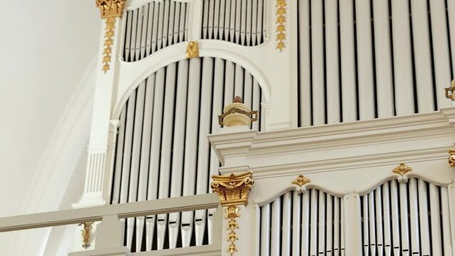 Slow tracking view of pipe organ at front of old Lutheran temple.