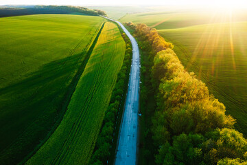 Bird's eye view of a morning country road passing through farmland and cultivated fields. - 785090107