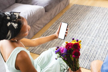 African American woman holding smartphone, showing screen on a video call date with copy space