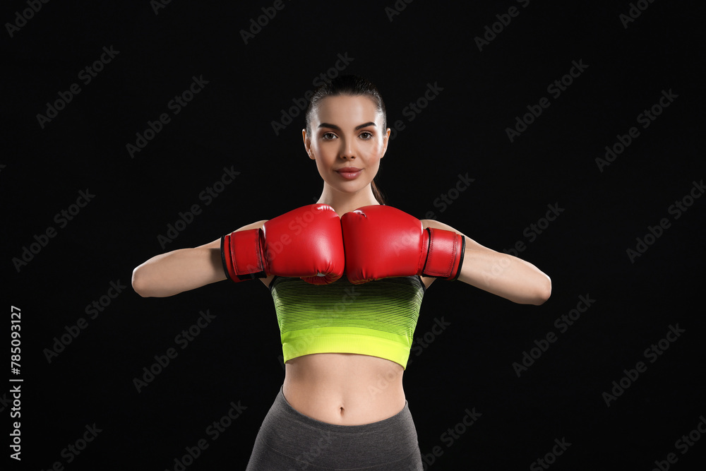 Poster Portrait of beautiful woman in boxing gloves on black background