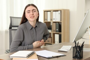 Woman having heart attack at table in office