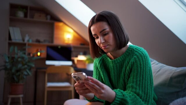 Portrait of beautiful young woman using mobile phone and texting message at evening home