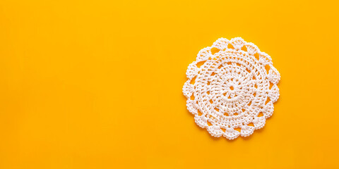 A white crochet doily on a yellow background.