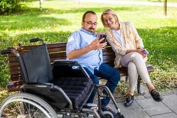 Man in wheelchair is spending time with his mother in park. - 785111315