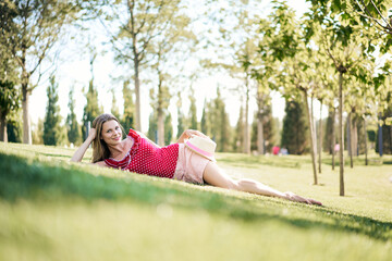 Portrait of a young woman laiying on green loan in the park. Summer activity