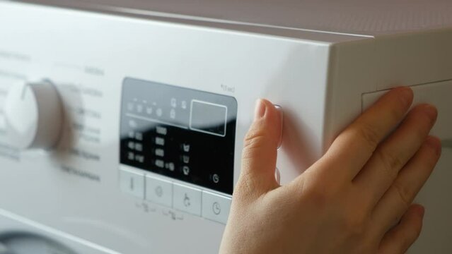 Pressing the start button on the washing machine close-up