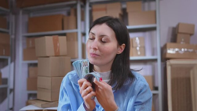a satisfied businesswoman counts banknotes against the background of the store's warehouse