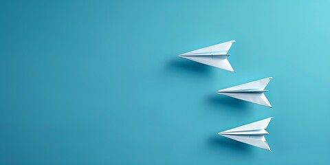 Three paper planes are flying in a blue sky. The planes are all white and have different sizes. The smallest plane is in the front, the medium plane is in the middle