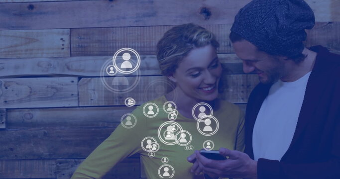 Image of social media icons over caucasian couple using smartphone