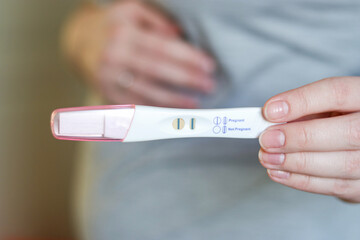 Close up of a pregnant woman holding a positive pregnancy test