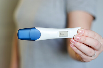 Close up of a happy woman holding a digital negative pregnancy test