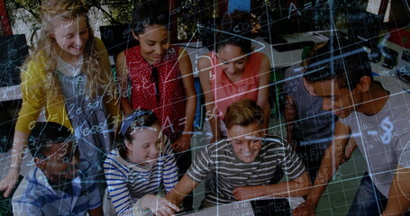 Image of math formulas moving over happy diverse pupils working on laptop