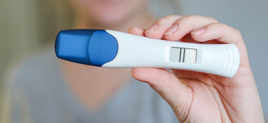 Close up of a happy woman holding a digital positive pregnancy test