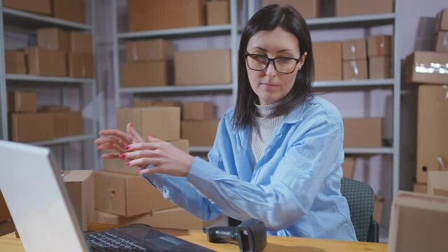 A young female warehouse worker uses a barcode scanner in her work close up