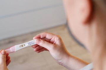 Close up top view of a woman holding a positive pregnancy test