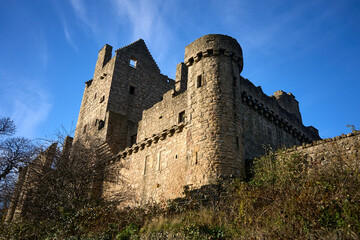 Craigmillar Castle. The image features a majestic stone castle on a hill, surrounded by greenery. With a sturdy wall and elegant tower, it exudes history and grandeur. © Valentine