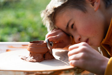 Boy trimming a piece of clay to make pottery on the potter's wheel